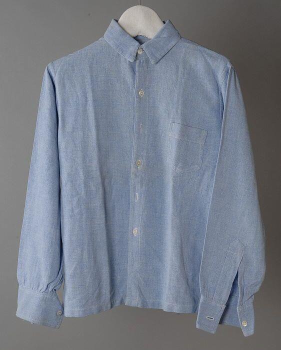 Jongensoverhemd van blauw-wit gemêleerd katoen(?) met opengewerkt ingeweven blokje, lange mouwen en…