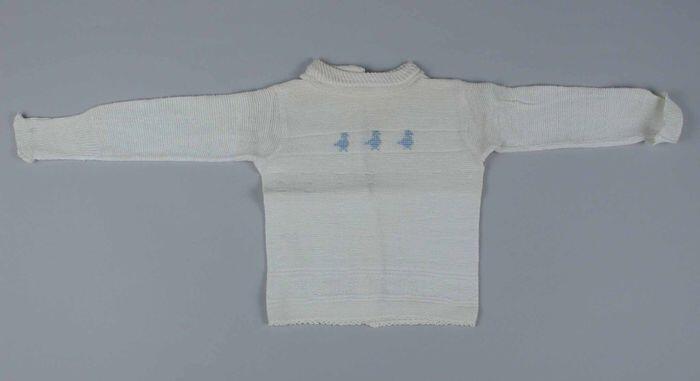 Babytrui gebreid van wit katoenin reliëf, lange mouwen, middenachter open, voorzijde in lichtblauw…
