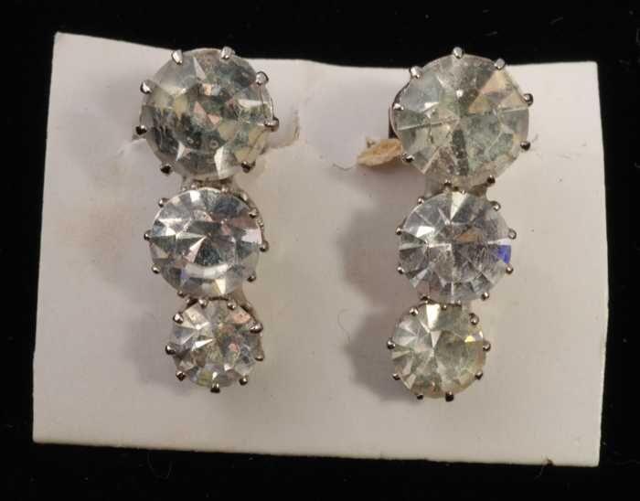 Eén paar oorbellen, clip met drie kunstdiamantjes in zilverkleurige metalen vattin, op wit karton,…