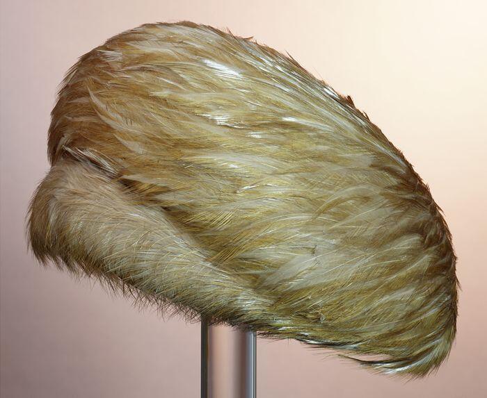 Toque, geheel bedekt met beige veren in spiraalvorm aangebracht