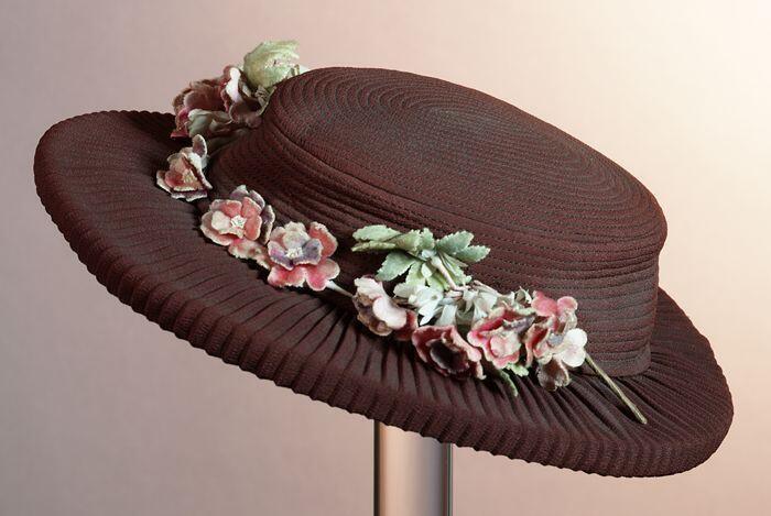 Dameshoed van rood-bruin crêpe met roze bloemcorsage van fluweel