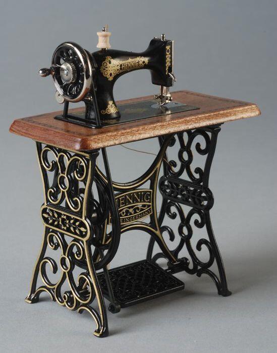 Gietijzeren miniatuur trapnaaimachine met houten werkblad en houten garenklosje los op machine,…