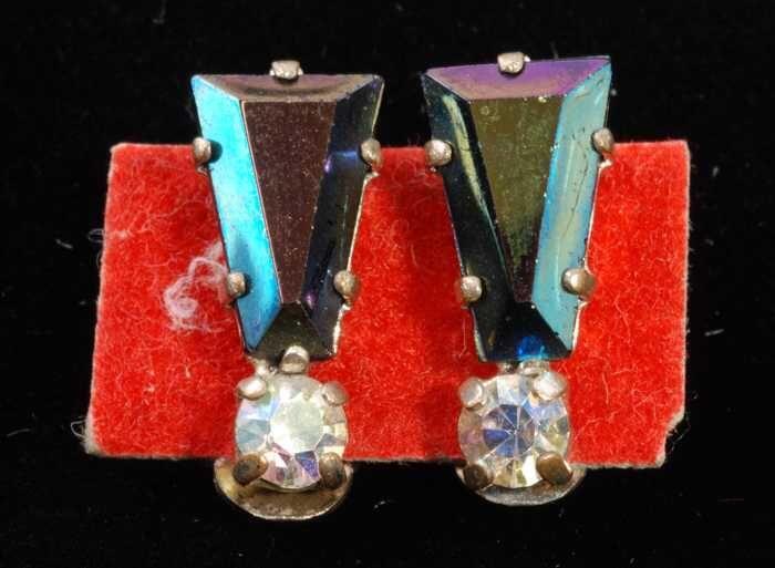 Eén paar oorbellen, clip met paarsblauwe facetsteen in zilverkleurige metalen vattin, op rood…