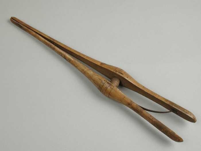 Handschoenrekker van hout twee spits toelopende poten met metalen veer