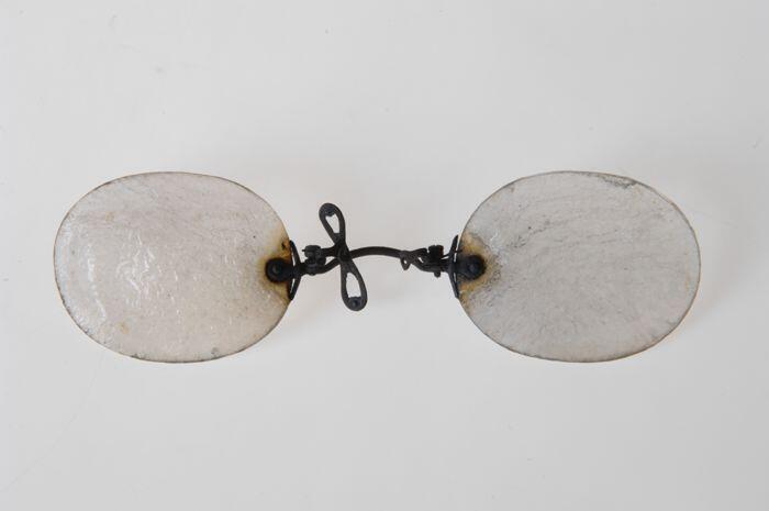 Pince-nez met glazen aan verend klemmende neusbrug, uit de brand van 14 mei 1940 afkomstig