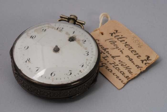 Zakhorloge met wit-emaille wijzerplaat en tweekleppige kast met opwindgat in wijzerplaat