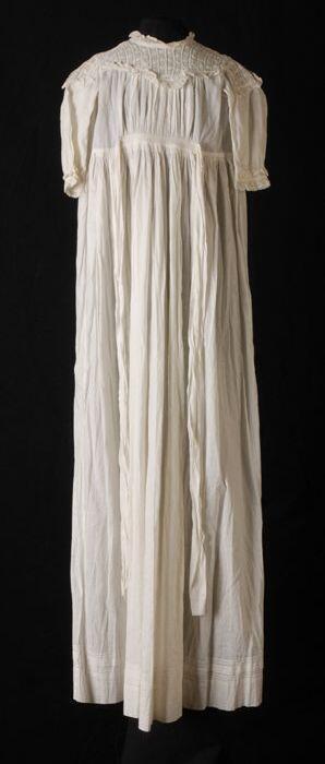 Doopjurk van wit katoen broderie anglaise en kant langs de pas, met aangerimpelde rok, lange mouwen…