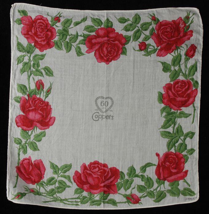Wit katoenen zakdoek met opdruk in rood en groen van rozentakken rondom en centraal "60 jaar…