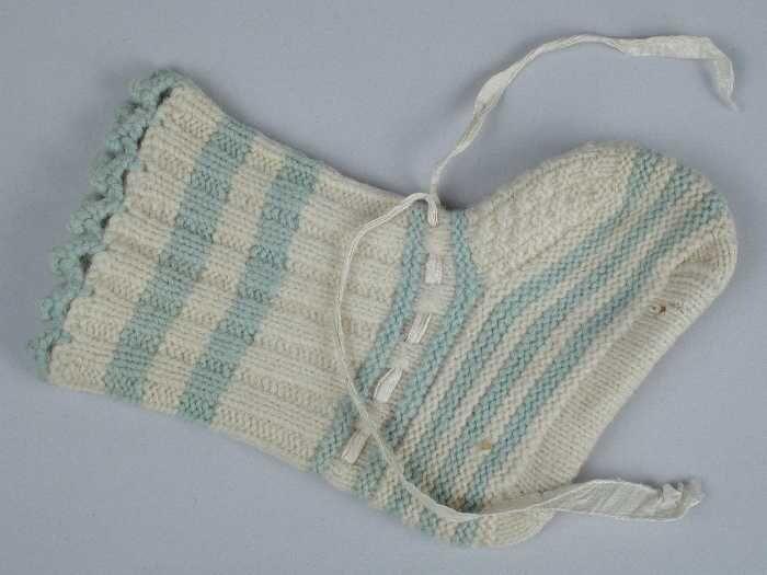 Paar babysokken gebreid van lichtblauwe en crèmekleurige wol in tricot- en ribbelsteek,wit…