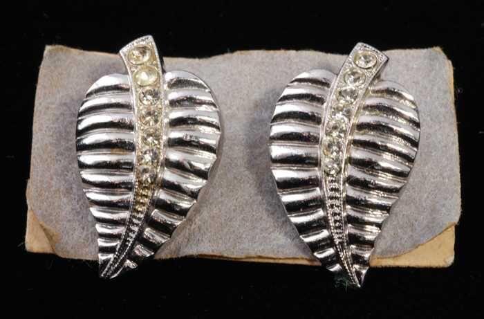 Eén paar oorbellen, clip met zilverkleurige metalen bladvorm met kleine kunstdiamantjes, op grijs…
