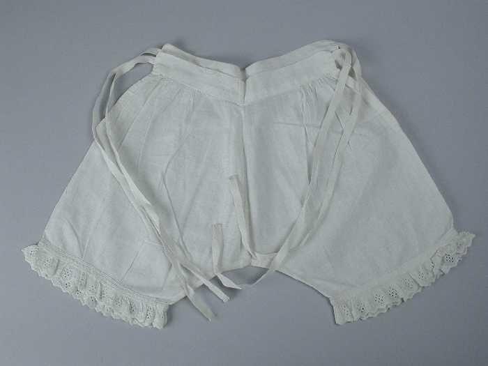 Kinderonderbroek van wit katoen strikbanden opzij, aangerimpeld broderie langs korte pijpen