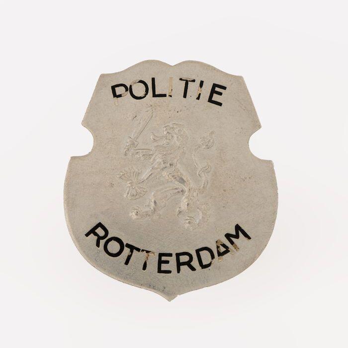 Metalen schildje, met leeuw en "politie Rotterdam", aan keerzijde"No. 1275"