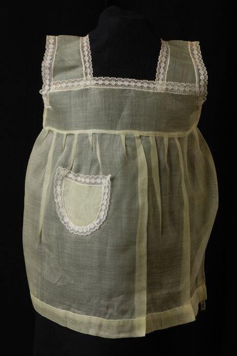 Babyjurk, mouwloos schortmodel van transparant geel nylonmet wit kant, 'Femifra' model 'Rola 1'