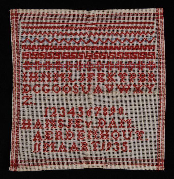 Letterlap gewerkt in kruissteek in rood en blauw katoenop een grof wit katoenen stramien in…