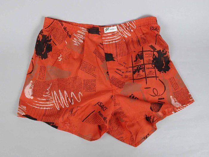 Boxershort van rode stof met dessin van zwarte en witte teksten, knoopgulp, "FOR SALE"