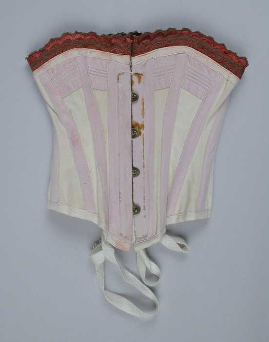 Poppenkorset of korsetmodel, klein gebaleineerd korset van wit katoen met lila baleinen en rood…