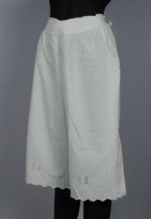 Dunne witte katoenen onderbroek met pijpen, versierd met broderie anglaise, sluit opzij met…