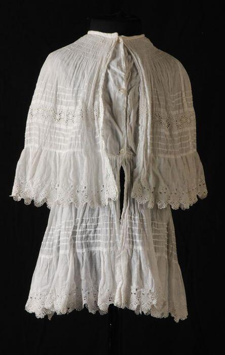 Kinderjurk of babyjurk van wit mousseline met oprijgjes en broderie en snijwerk aan de zoom, brede…