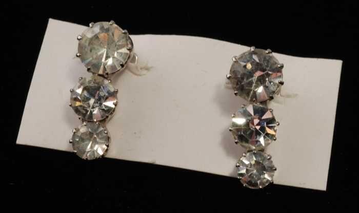 Eén paar oorbellen, clip met drie kunstdiamantjes in zilverkleurige metalen vattin, op wit karton,…