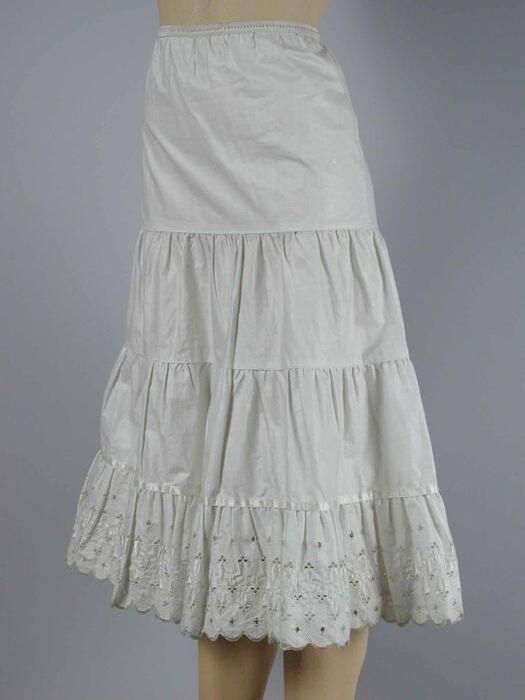 Witte batisten petticoat, opgebouwd uit aangerimpelde stroken, onderste van geschulpt broderiekant…