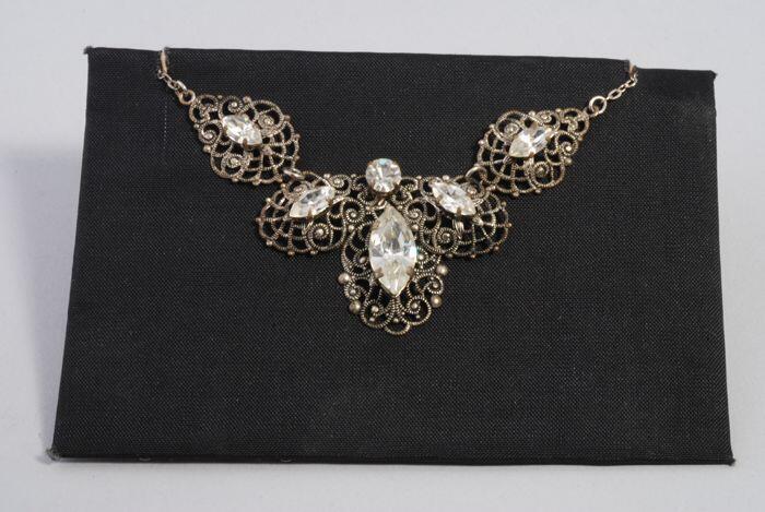 Halsketting met amandelvormige kunstdiamantjes op zilverkleurige filigrein ornamenten, kapper Van…