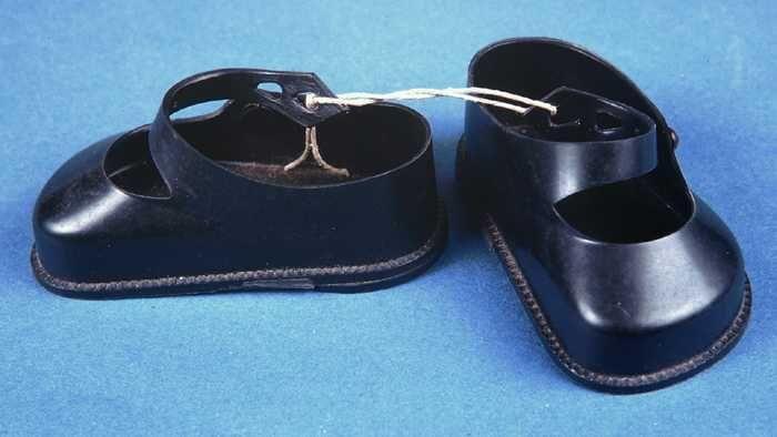 Paar miniatuur schoenen van zwart plastic, plat model met wreefbandje, poppengoed, "Cinderella"