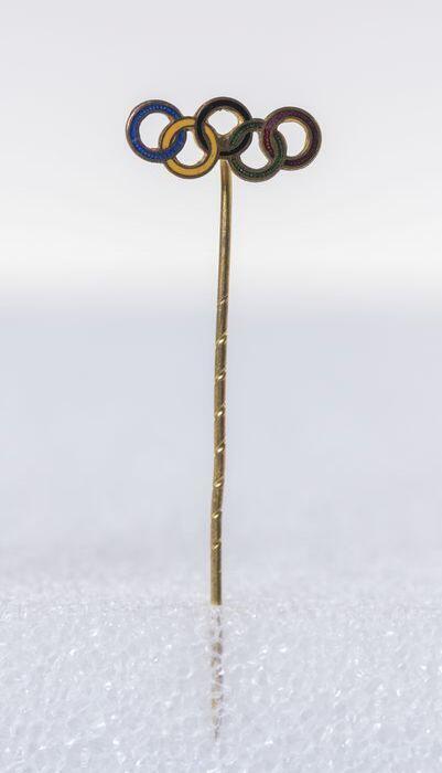 Messing sierspeld, dasspeld, met in emaille de vijf gekleurde ringen van de Olympische Spelen