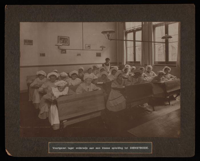 Grote zwart-wit foto geplakt op matzwart karton, met klaslokaal van de School voor Vrouwenarbeid