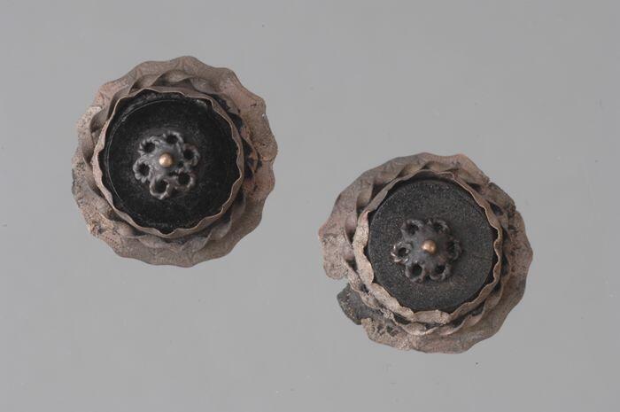 Twee oorbellen uit doosje van metaal met open gesprongen deksel, waarin verder vijf dubbeltjes en…