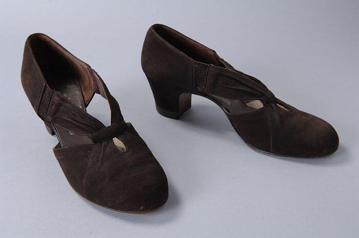 Bruine suède hakschoenen, hoog gesloten op de wreef, vanaf de neus twee geplooide bandjes naar de…