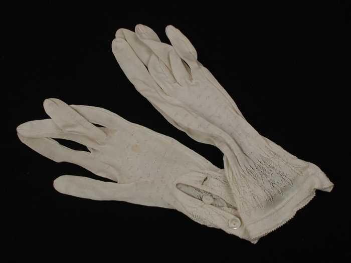 Paar korte dameshandschoenen van wit tricot kunstzijde in ajour gebreid, twee paarlemoeren knoopjes