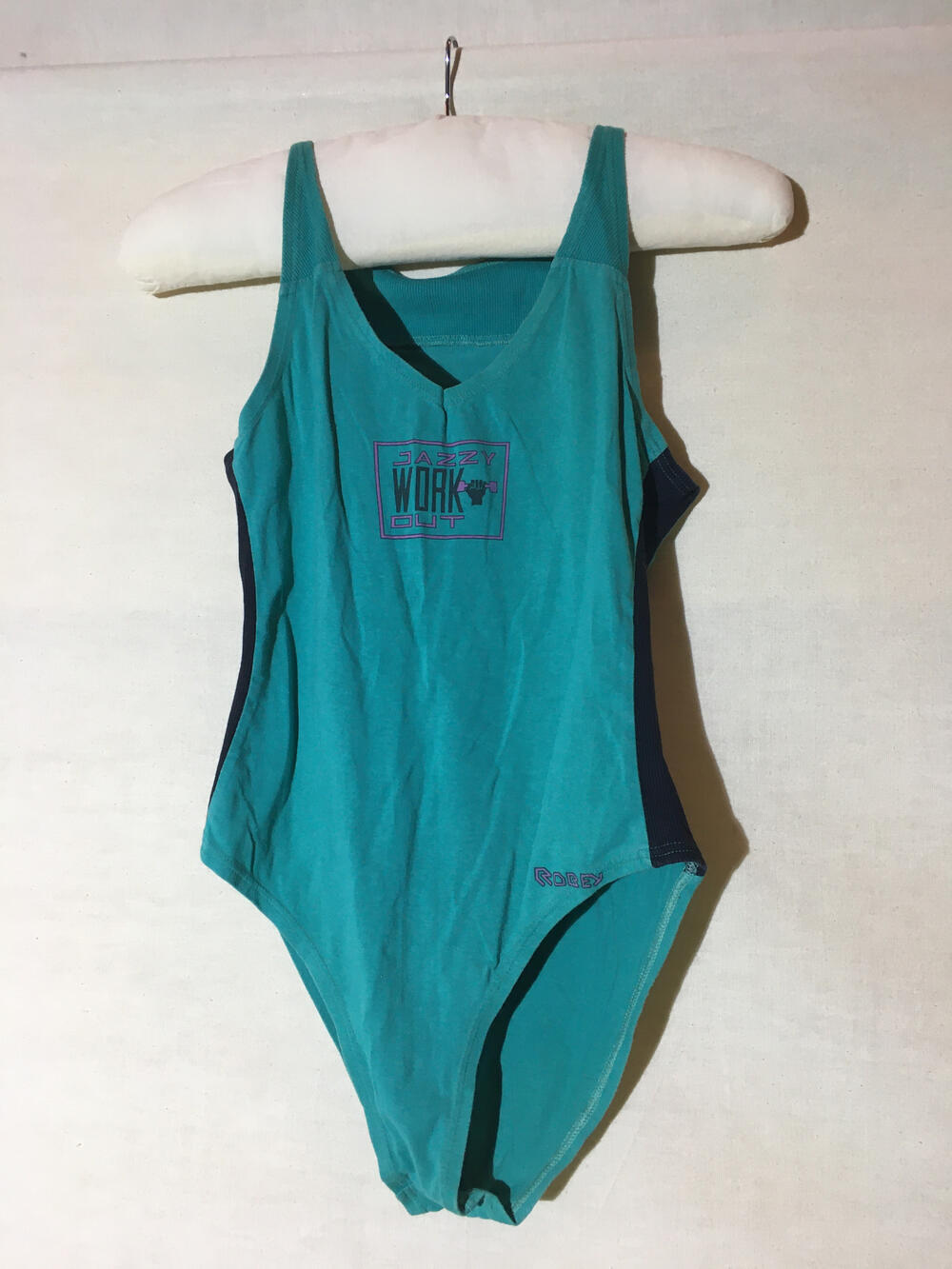 Jazz balletpakje. Groene katoenen tricot. Zijkanten van zwarte rib tricot. Middenvoor tekst: "Jazzy…