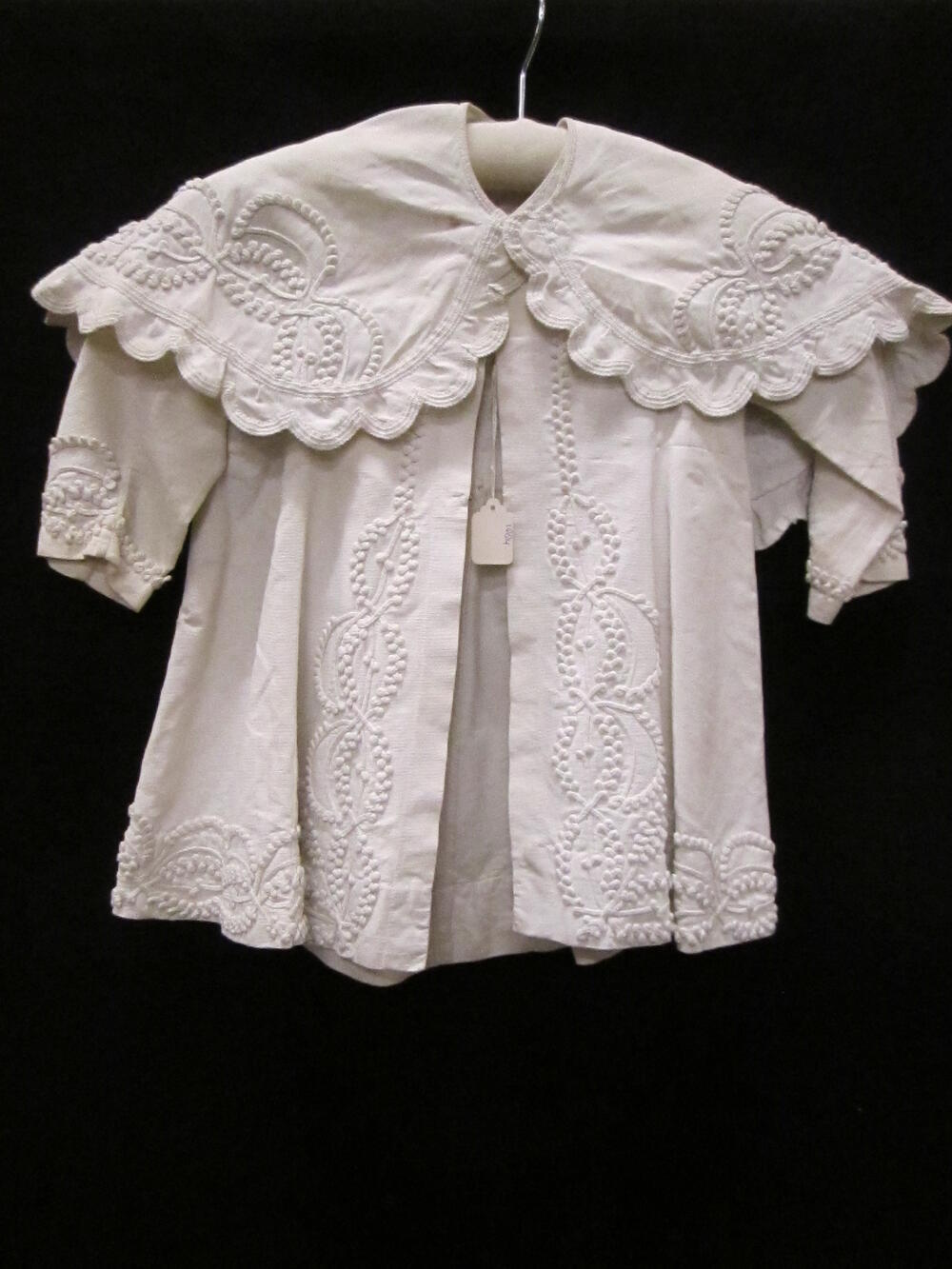Jas (kind) met losse pelerine van wit katoenen piqué, gegarneerd met witte soutache