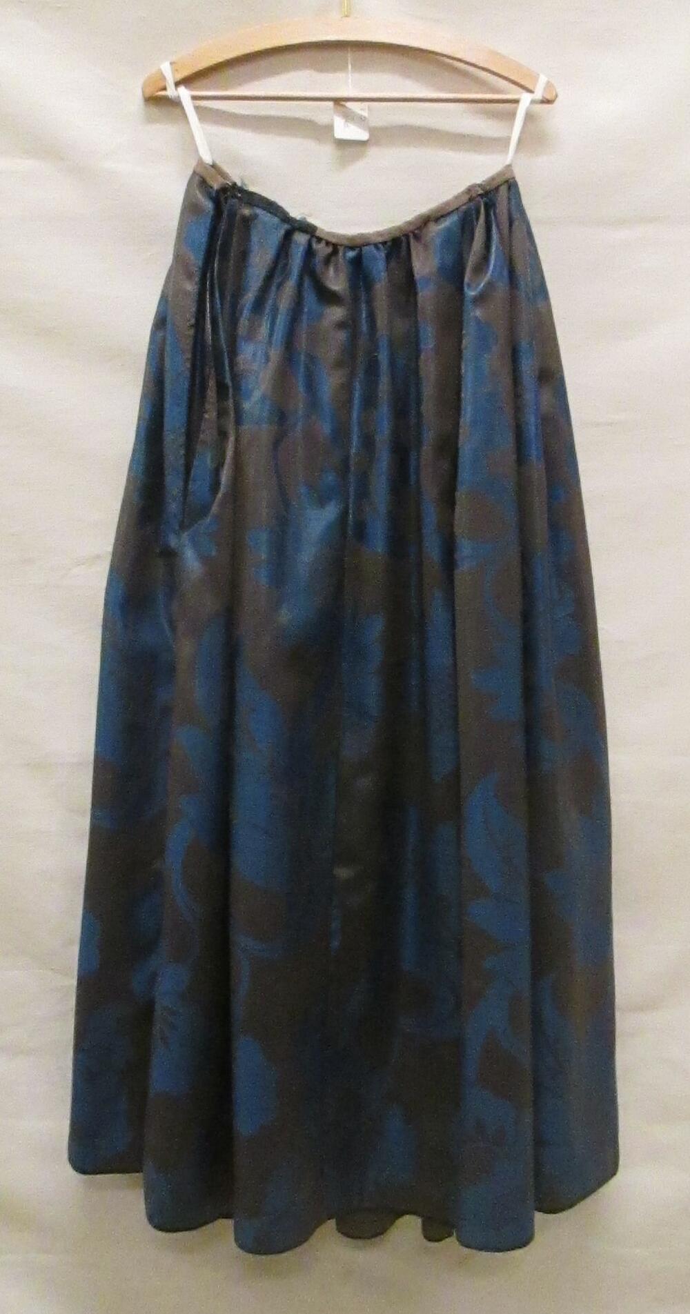 Rok van zwarte en donkerblauw geglansd wollen damast met zeer grote florale motieven. Voorpand vlak…