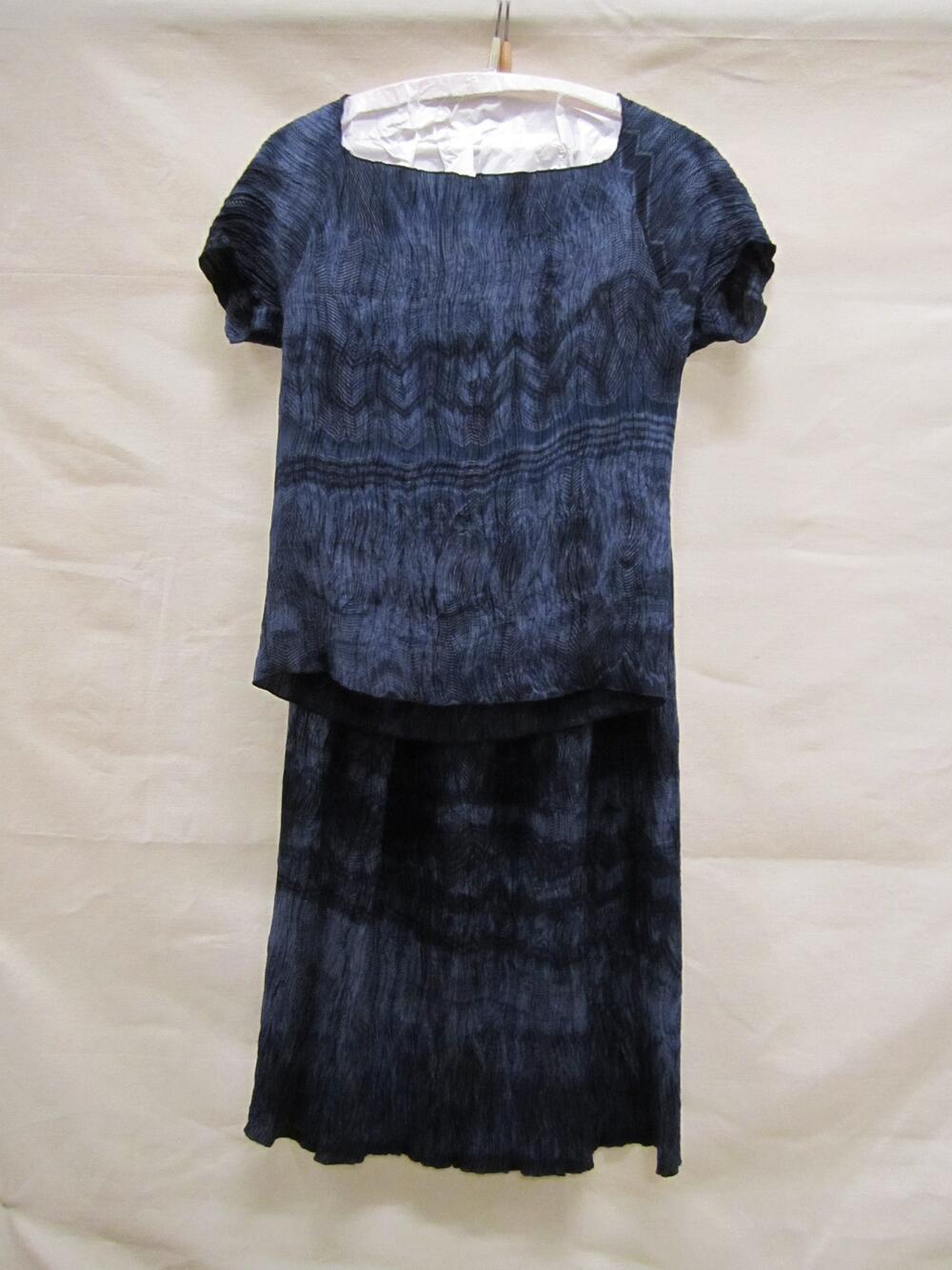 Ensemble van zijde met blauw fond en donkerblauwe lijnen, bestaande uit blouse en rok