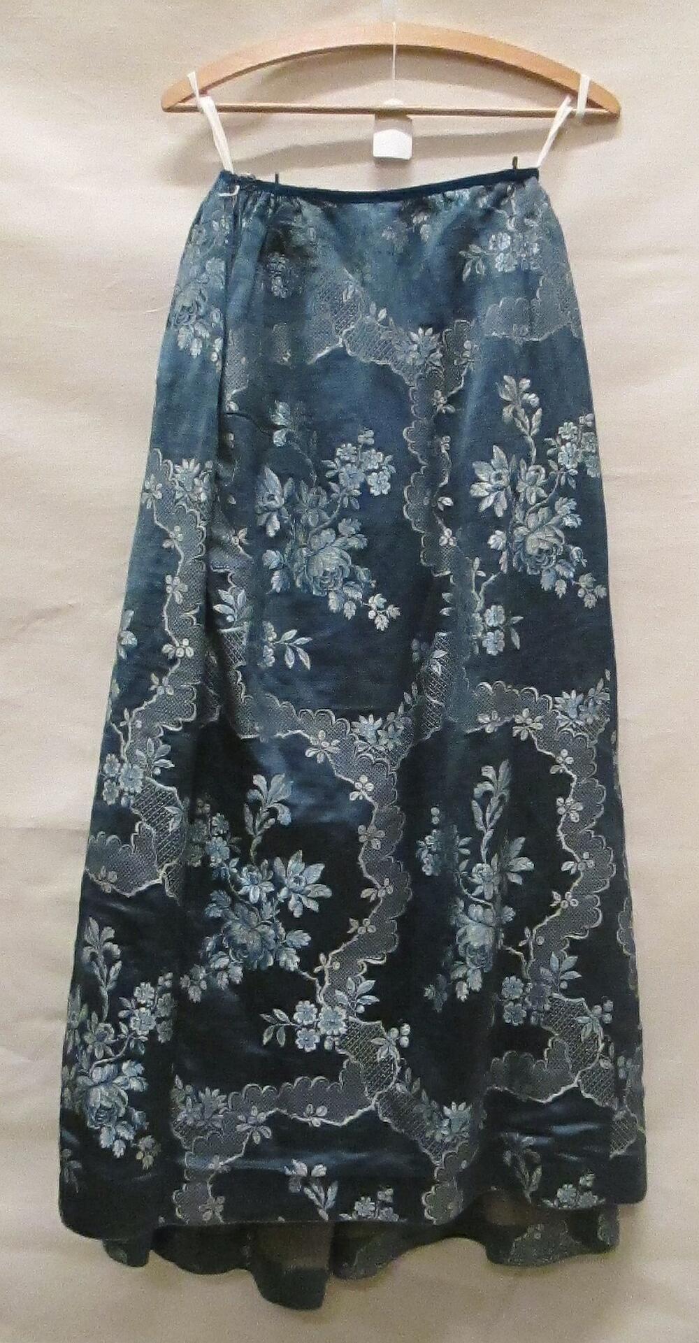 Rok van blauw zijden damast met witte en lichtblauwe gebrocheerde zijden bloemtakken en geschulpte…