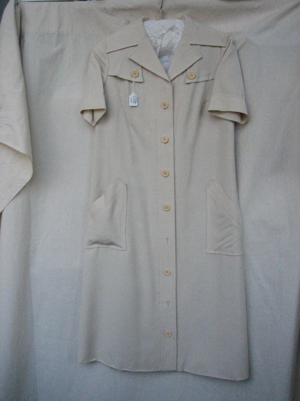 Jurk van beige fibranne, hemdmodel met reverskraag en korte mouw met strikceintuur van idem stof
