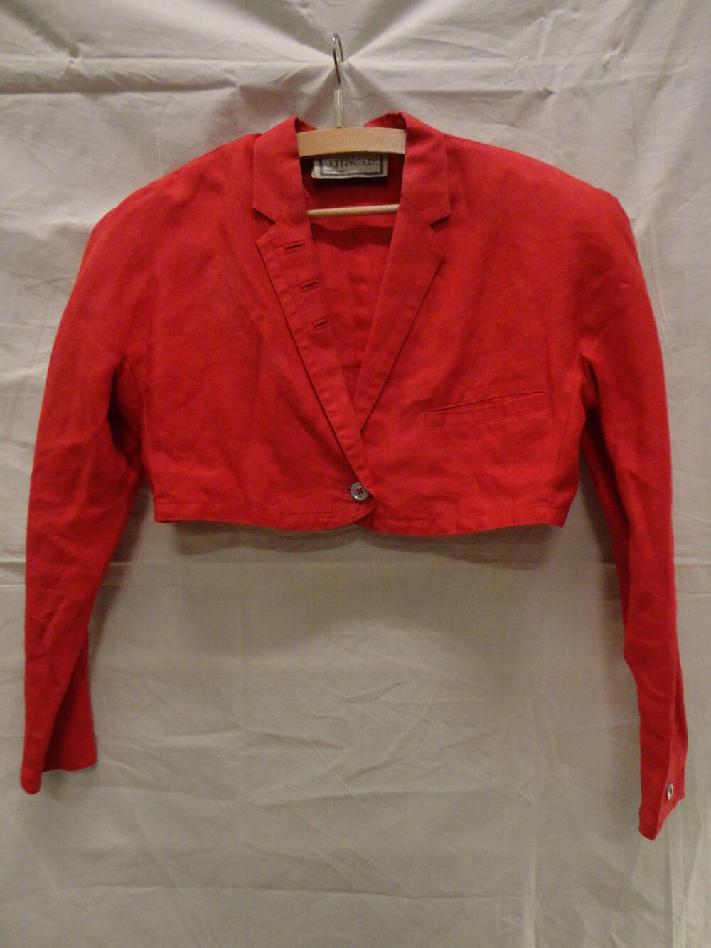 Bolero, of kort jasje van rood linnen, lange aangeknipte mouwen en reverskraag, welke versierd met…