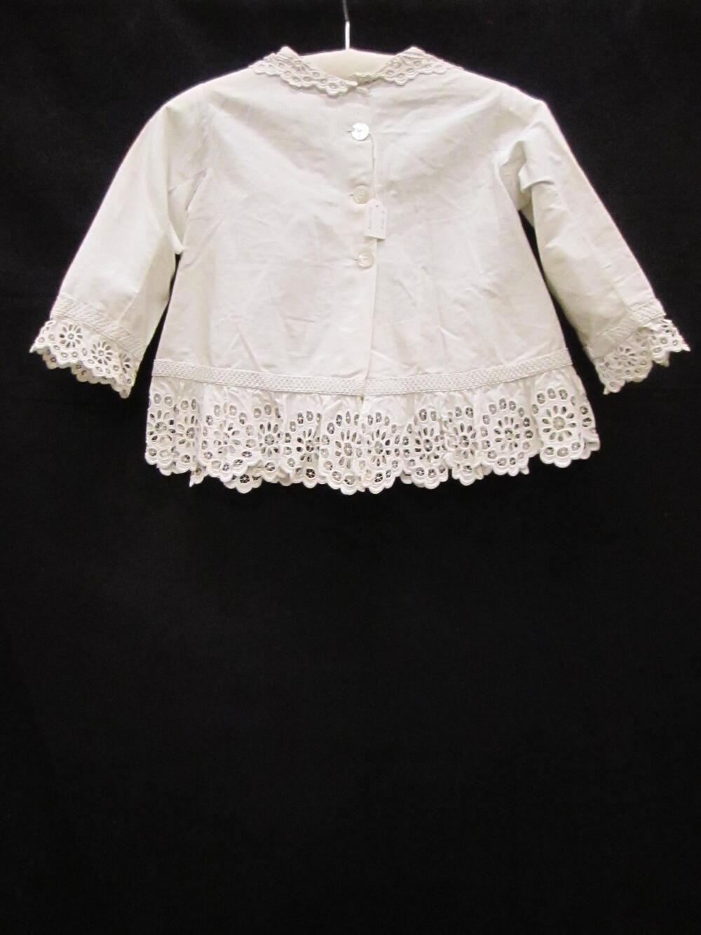 Manteltje / Jasje (kind) van wit katoenen piqué, afgezet met Engelse broderie en soustache