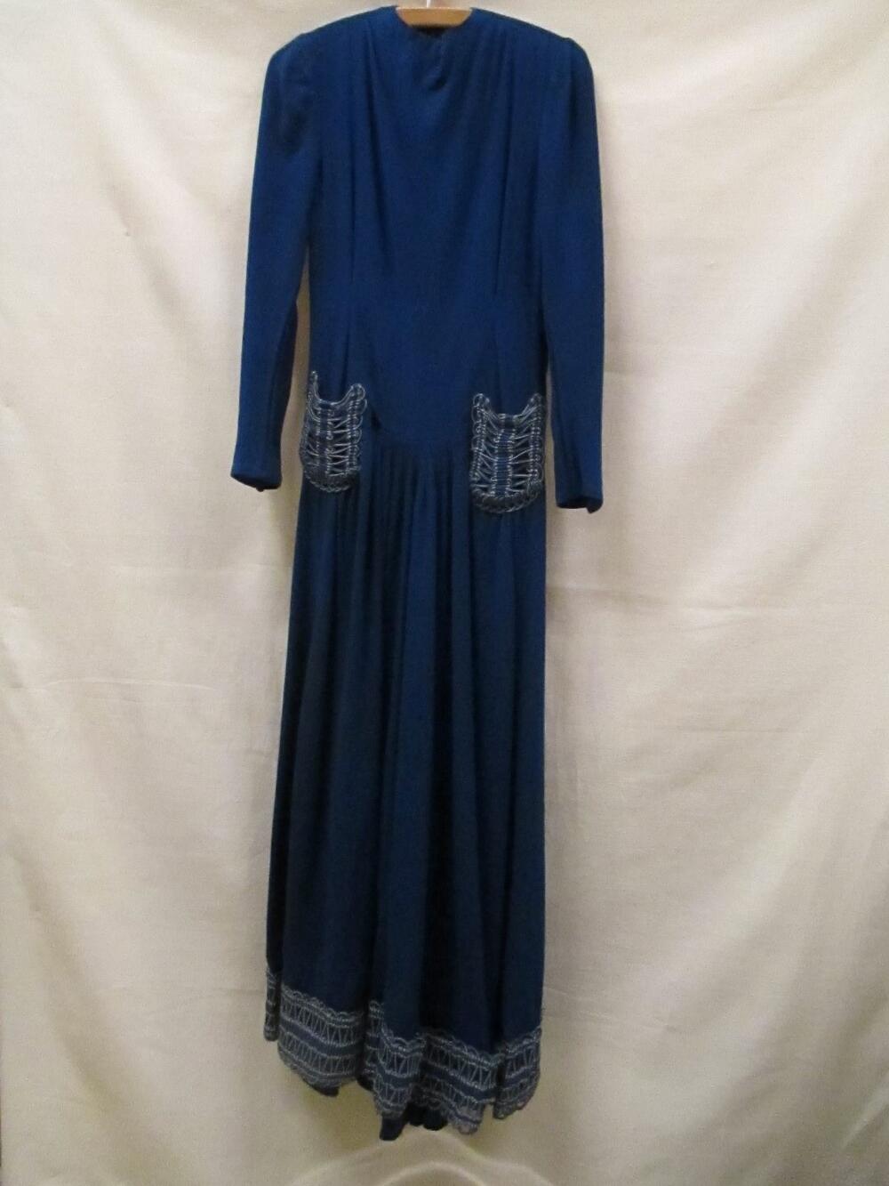 Jurk van blauwe wol, lang model met garnering van blauw koord en blauwe kwastjes