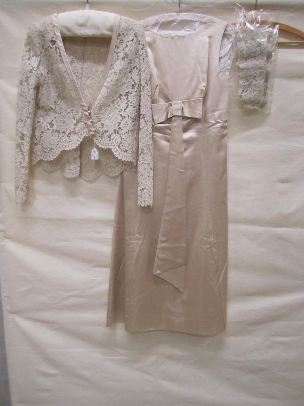 Trouwensemble bestaande uit jurk, jasje, hoed en 1 paar mitaines van lichtbeige satin duchesse en…
