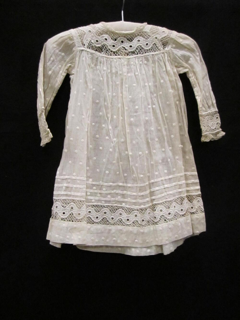 Jurk (kind) van wit katoen met garneringen van broderie, kant en stippeltjesborduursel