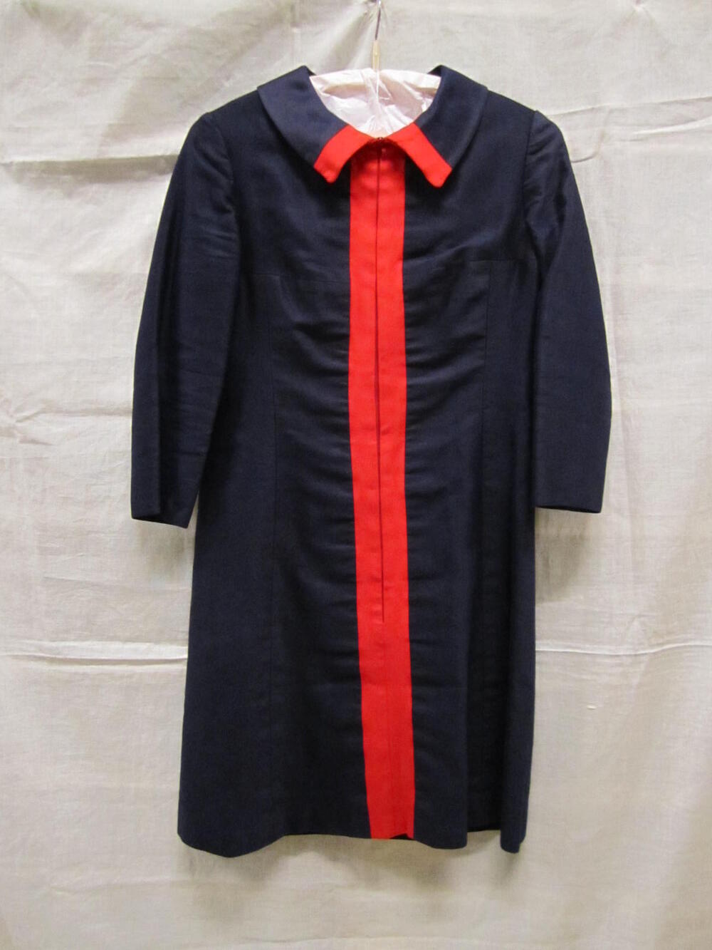 Robe-manteau van donkerblauwe katoen in satijnbinding, met brede rode bies middenvoor en op kraagje
