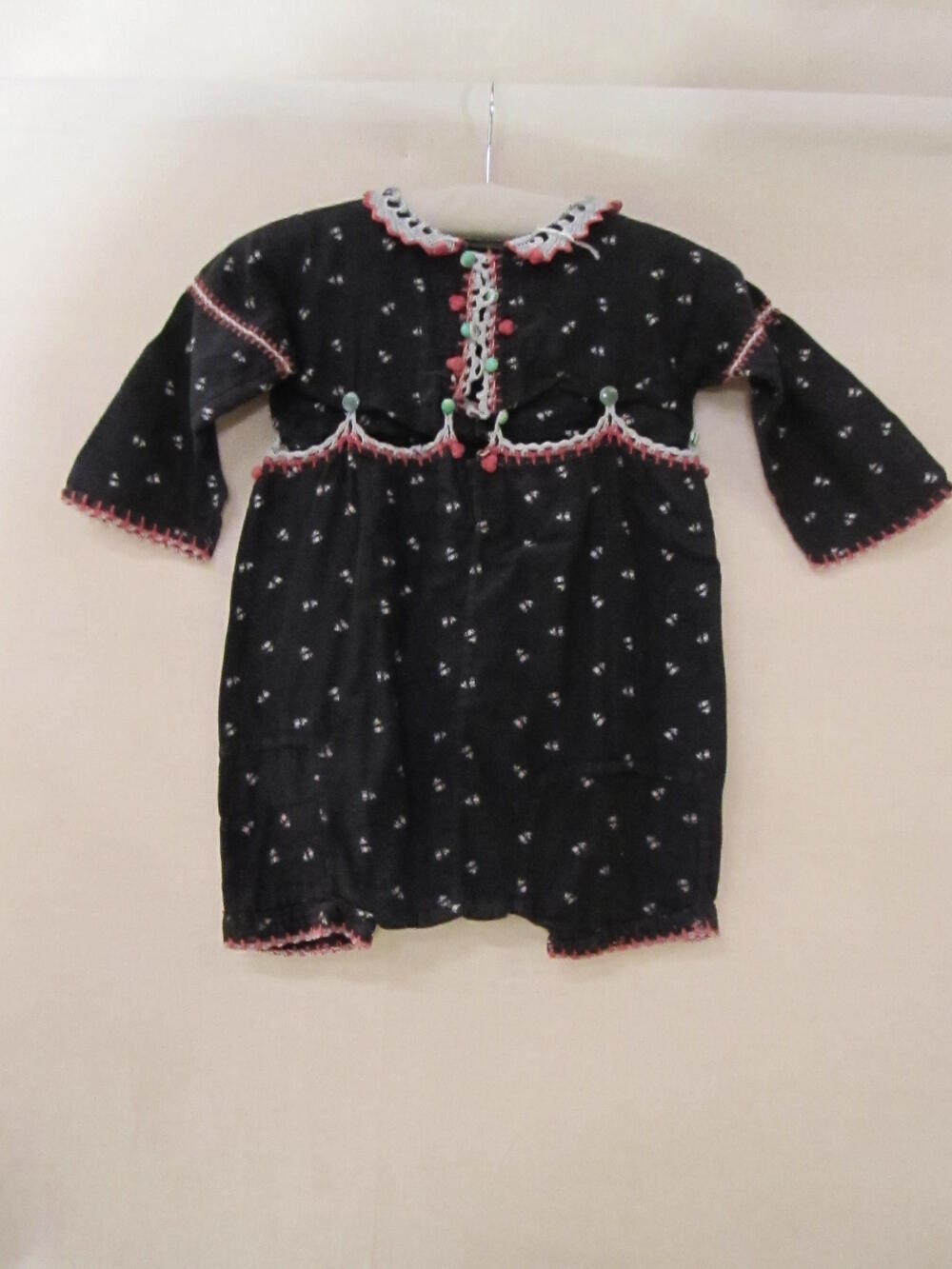 Peuterpakje bestaande uit blouse en broek van zwart flanel met roze bloemetjes