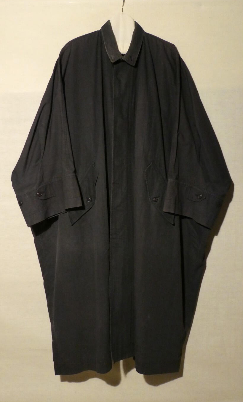 Jas (man) van antracietkleurig katoen. Zeer wijd model met aangeknipte mouwen