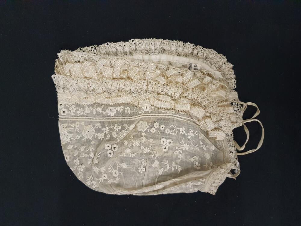 Meisjesmuts, circa 10 jaar, wit neteldoek geborddurd met bloemenrandje in plumetis, voorrand…