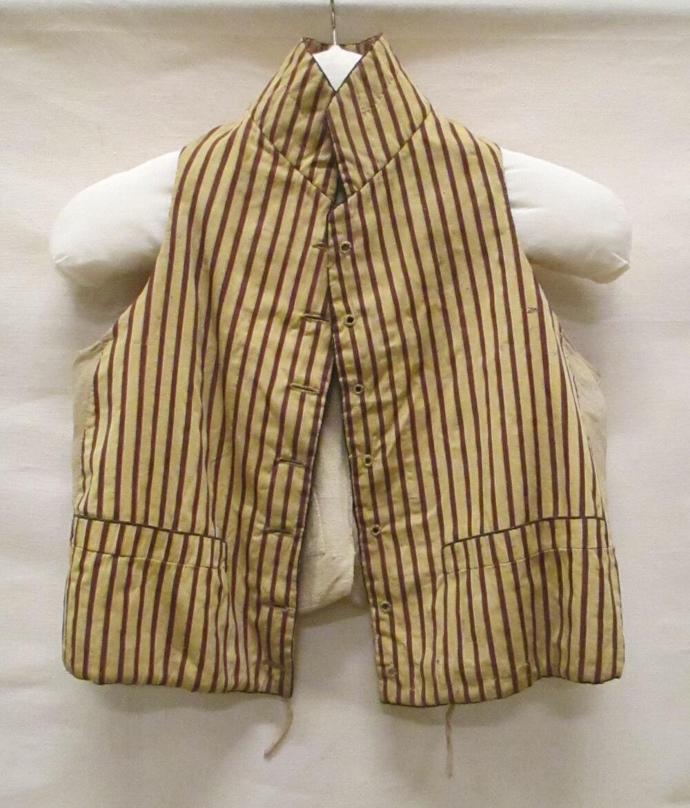 Vest (man) van gele zijde met bruin/rood/witte streep, achterpand en voering van wit katoen