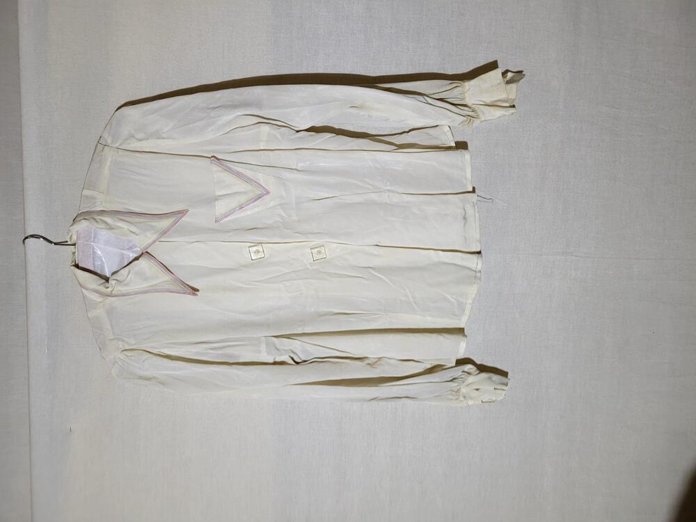 Blouse van crèmekleurige kunstzijde, langs de kraag en op het borstzakje een stiksel in rood, groen…