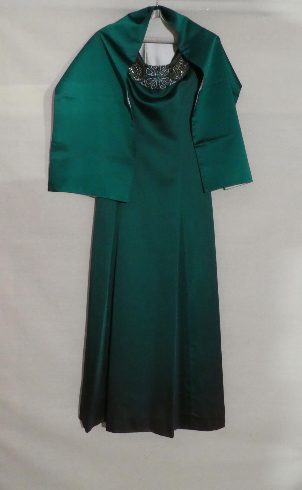 1) Avondjurk van donkergroene satin duchesse. Lang, gerend, mouwloos model met wijde ovale hals,…