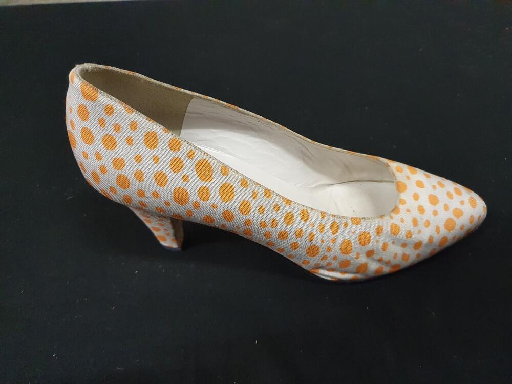 Een paar schoenen, model pump van leer bekleed met witte stof bedrukt met oranje stippen, smal…
